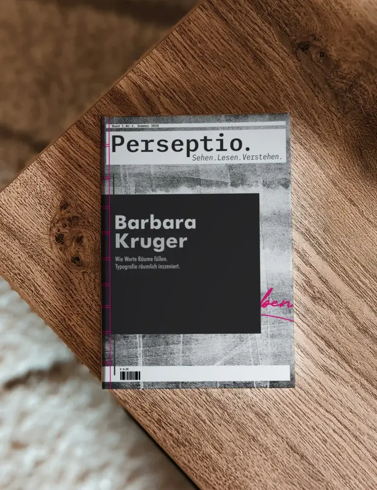 Cover des gedruckten Perseptio Magazins mit dem Titelthema Barbara Kruger, liegend auf einem rustikalen Holztisch aus der Vogelperspektive.