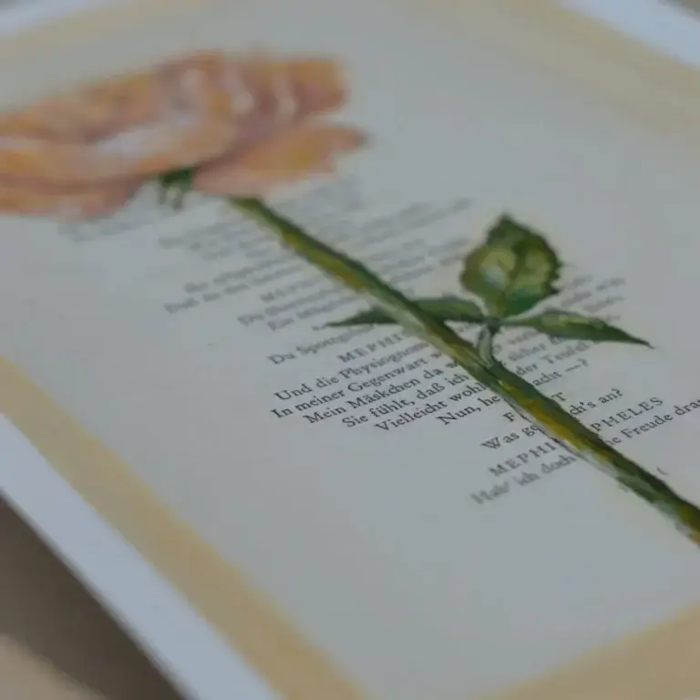 Eine Buchseite mit gedrucktem Theatertext aus Goethes „Faust“, überlagert von einer detaillierten botanischen Illustration einer pfirsichfarbenen Rose mit grünem Stiel und Blättern.