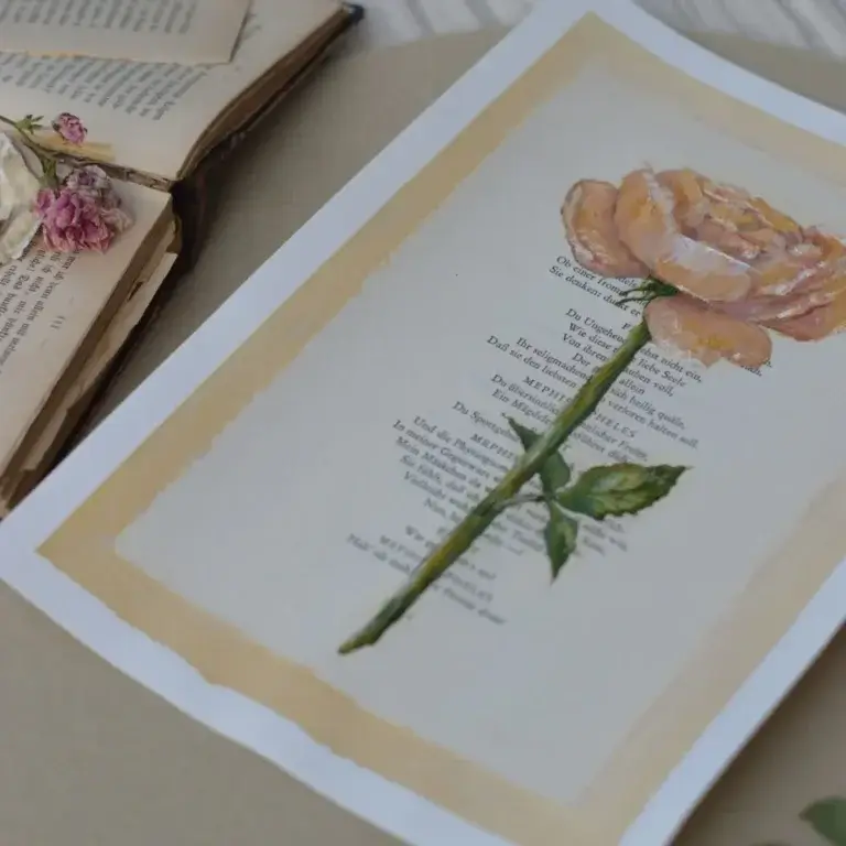 Eine Buchseite mit gedrucktem Theatertext aus Goethes „Faust“, überlagert von einer detaillierten botanischen Illustration einer pfirsichfarbenen Rose mit grünem Stiel und Blättern.