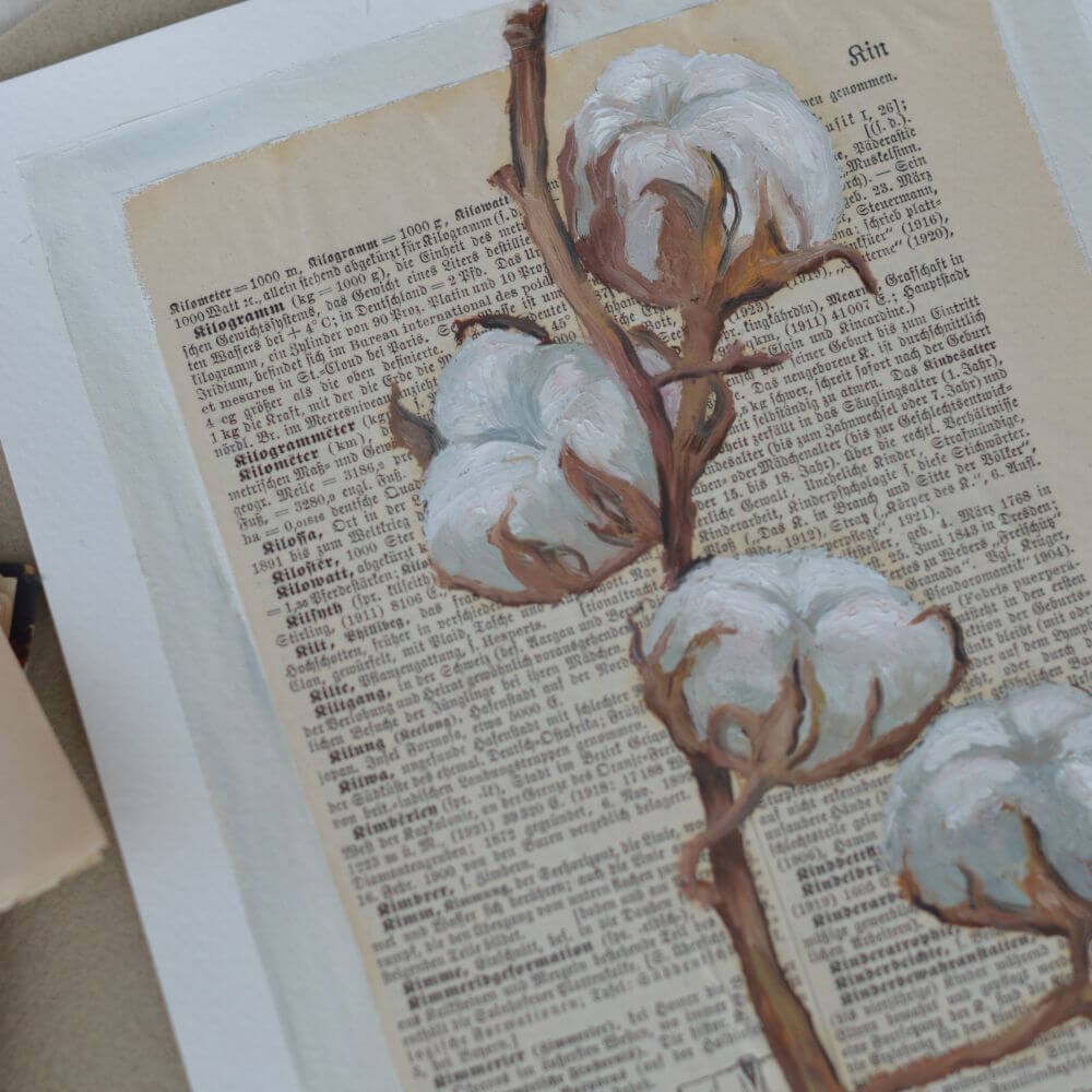 Ölgemälde eines detailreichen Baumwollzweigs mit weißen, flauschigen Blüten, gemalt auf eine alte, vergilbte Buchseite in deutscher Frakturschrift. Im unteren Bereich ist eine dezente Skizze eines Mantels zu sehen
