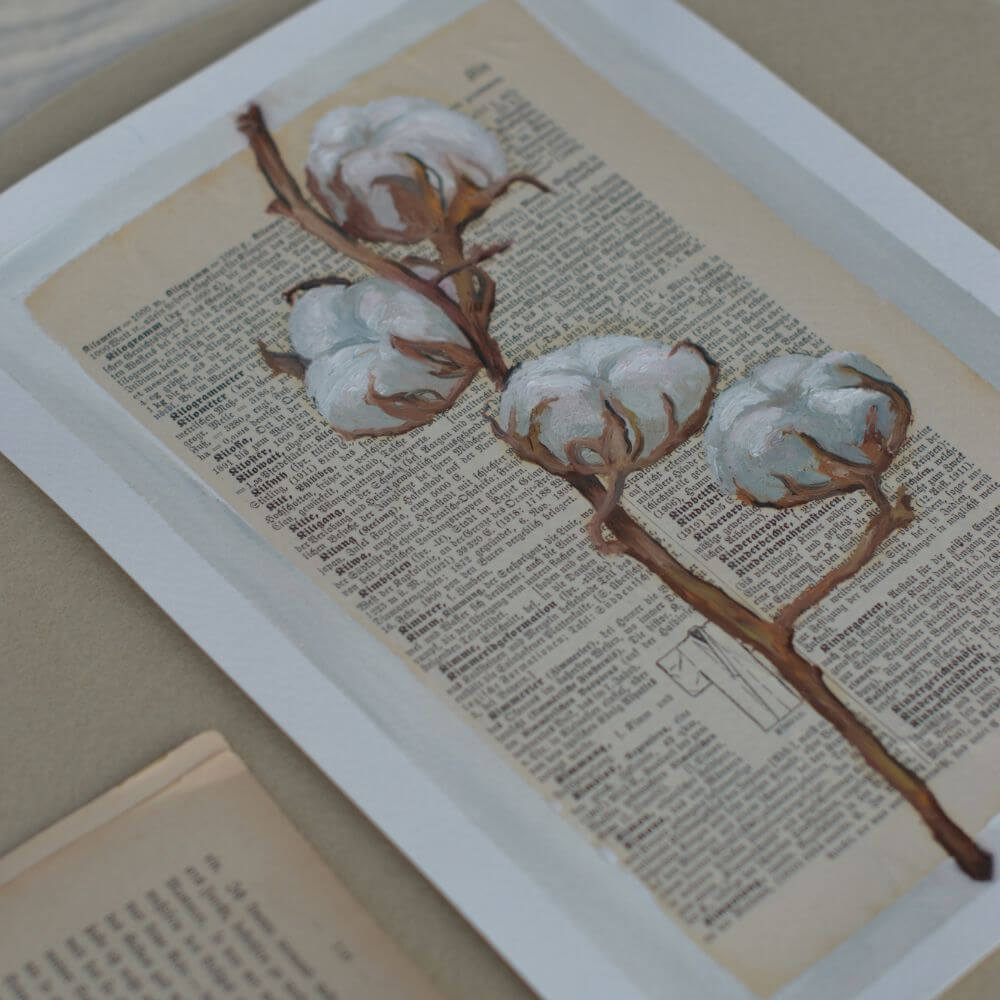 Ölgemälde eines detailreichen Baumwollzweigs mit weißen, flauschigen Blüten, gemalt auf eine alte, vergilbte Buchseite in deutscher Frakturschrift. Im unteren Bereich ist eine dezente Skizze eines Mantels zu sehen.