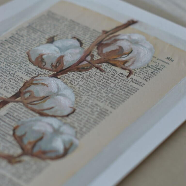 Ölgemälde eines detailreichen Baumwollzweigs mit weißen, flauschigen Blüten, gemalt auf eine alte, vergilbte Buchseite in deutscher Frakturschrift. Im unteren Bereich ist eine dezente Skizze eines Mantels zu sehen.