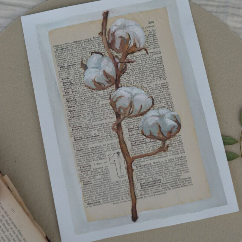 Ölgemälde eines detailreichen Baumwollzweigs mit weißen, flauschigen Blüten, gemalt auf eine alte, vergilbte Buchseite in deutscher Frakturschrift. Im unteren Bereich ist eine dezente Skizze eines Mantels zu sehen.